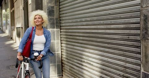 Urban Woman Walking Bicycle on City Street with Casual Vibe