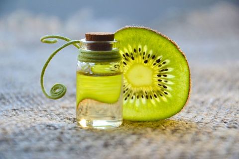 Kiwi Fruit with Essential Oil Bottle on Textured Surface