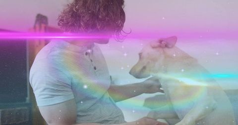 Man embracing dog on sofa with magical rainbow flares