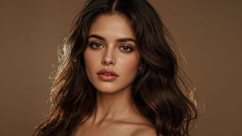 Elegant beautiful lady in strapless top on brown backdrop glowing softly