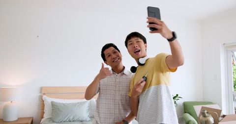 Father and son joyfully unpacking boxes in new home bedroom