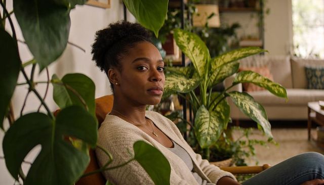 Woman relaxing in armchair surrounded by lush houseplants and cozy living room