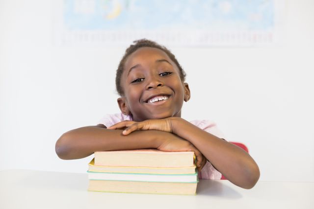 Portrait of smiling girl with books in classroom at school