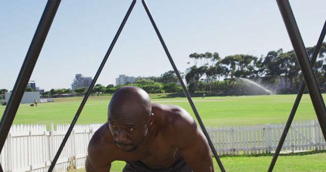 Tired fit shirtless african american man cross training outside, resting. cross training for fitness at a sports field.