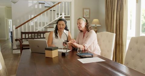 Two women unboxing gift at home sharing joy together