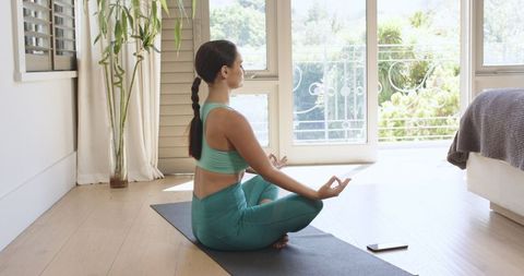 Young Woman Practicing Yoga at Home with Smartphone
