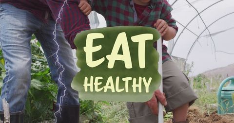 Father teaching son sustainable farming techniques in greenhouse
