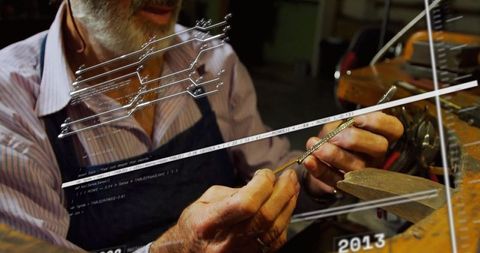 Artisan craftsman filing metal in workshop for jewelry making