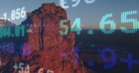 Stock market data projections on red sandstone monolith at sunset