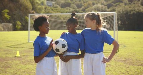 Diverse Girl Soccer Teammates in Blue Uniforms on Grass Field
