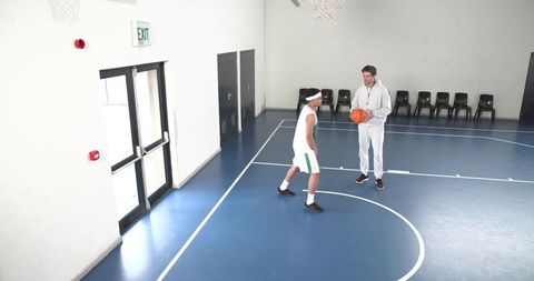 Coach guiding young athlete on basketball court for training