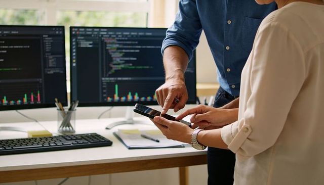 Collaborating on code and analytics using smartphone with dual monitors displaying charts