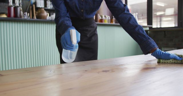 African american woman wearing gloves and apron disinfecting tables at cafe bar - Download Free Stock Photos Pikwizard.com
