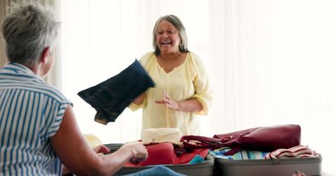 Senior Lesbian Couple Packing for Vacation in Bright Bedroom