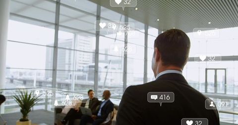 Executive observing team collaborating in modern office lobby with social media icons