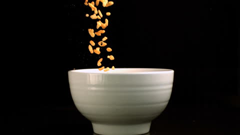 Rice Cereal Dropping Into White Bowl in Dramatic Slow Motion