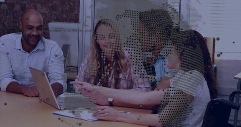 Diverse team collaborating over laptop in modern office meeting around table