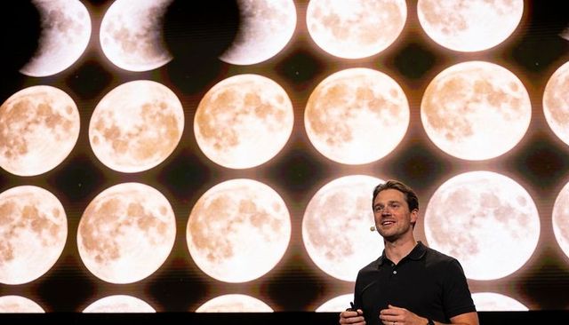 Keynote speaker presenting on stage with moon backdrop, confident speaking at conference