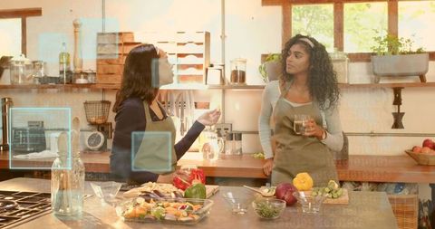 Two women cooking together in sunlit rustic kitchen preparing fresh vegetables on island