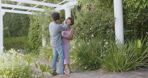 Romantic Couple Embracing in Lush Garden Setting on Sunny Day