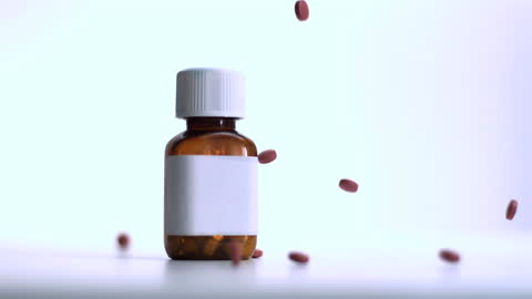 Red Pills Falling Around Amber Vial in Slow Motion