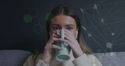 Woman drinking coffee with digital network overlay