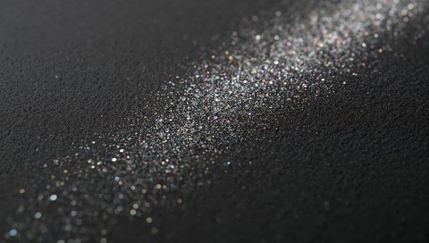 Diagonal Iridescent Glitter Trail on Textured Black Surface, Macro Sparkle Bokeh Background
