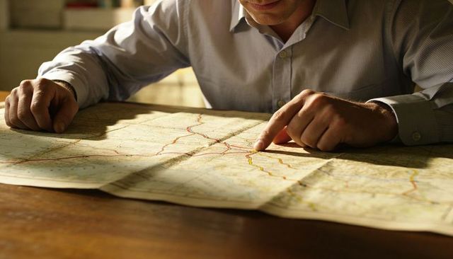 Tracing routes on folded road map in warm sunlight for travel and logistics planning