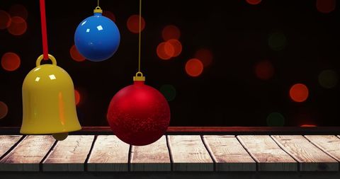 Colorful christmas baubles with bokeh and wooden surface