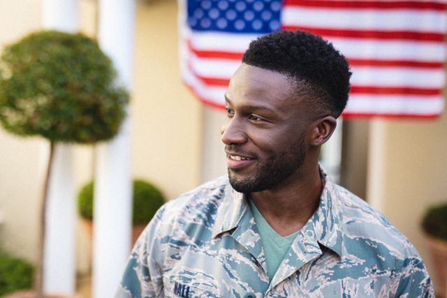 This image captures a smiling African American soldier in uniform with a US flag in the background. Ideal for use in content related to military service, patriotism, homecoming celebrations, and honoring veterans. Suitable for websites, articles, and promotional materials focusing on the armed forces and national pride.