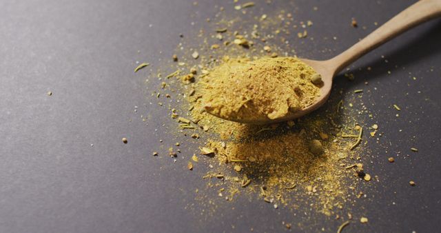 Image of spoon with tumeric seasoning lying on grey surface. cooking, seasonings, spices, taste and flavour concept.