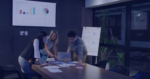 Team collaborating around laptop analyzing sales charts and financial data for planning