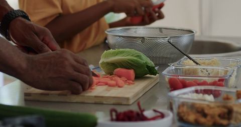 African american father and son chopping carrots and romaine on cutting board kitchen prep