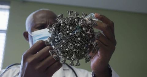 Masked clinician drawing vaccine from vial with 3d coronavirus wireframe overlay