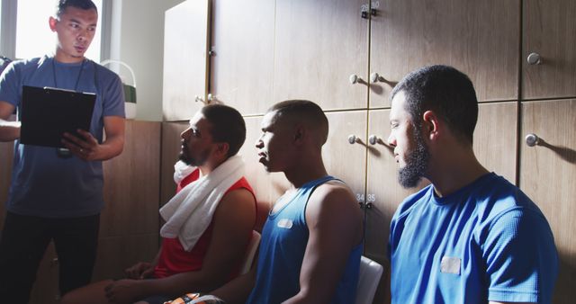 Diverse male football players discussing game with coach in changing room - Download Free Stock Photos Pikwizard.com