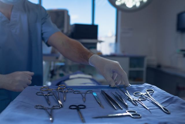 Mid section of male surgeon holding surgical instrument in operating room