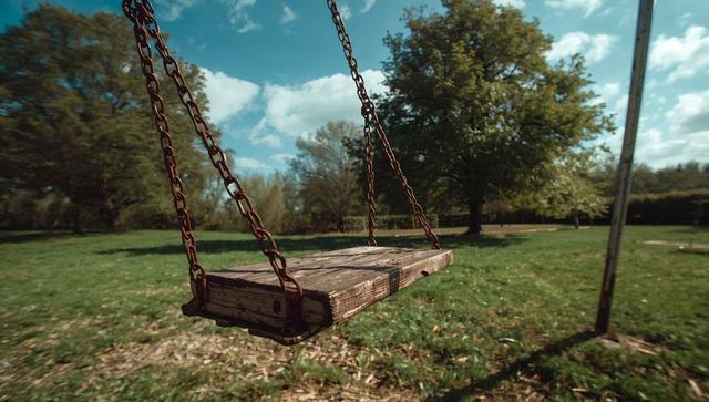 Swinging Weathered Wooden Seat with Rusty Chains in Sunny Grassy Park Rustic Closeup
