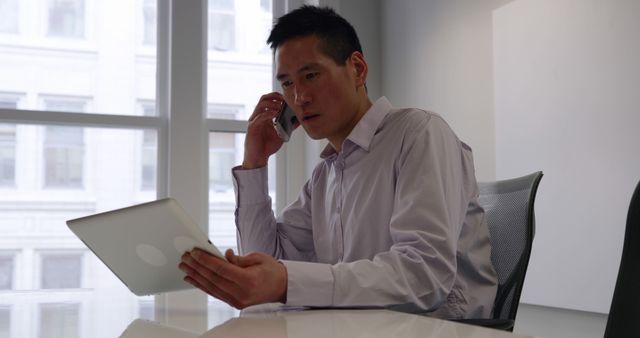 Businessman multitasking with tablet and phone in modern office - Download Free Stock Images Pikwizard.com