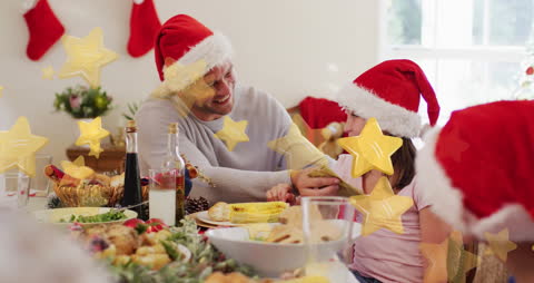 A joyful family wearing Santa hats sharing a festive Christmas dinner, surrounded by holiday decorations and lights. The animated stars add a whimsical touch to the warm atmosphere. Ideal for promoting holiday-themed products, family gatherings, or festive home decor.