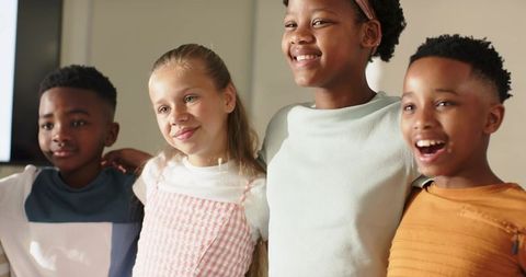 Smiling multiracial children linking arms in sunlit classroom learning moment