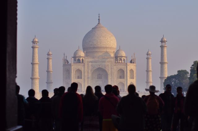 Tourists standing and observing Taj Mahal during sunrise. Used for travel blogs, cultural heritage articles, promotional material for tour agencies, and studies on historical monuments.