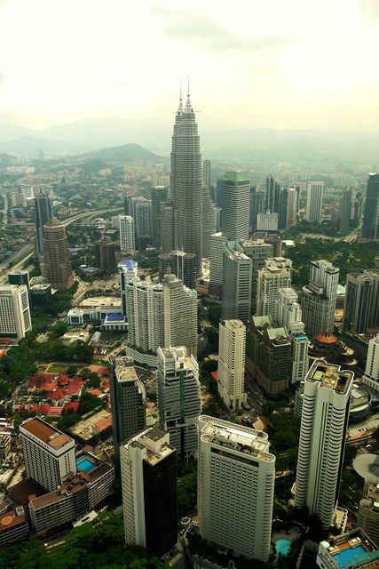 Aerial view of Kuala Lumpur featuring iconic Petronas Towers surrounded by skyscrapers and urban landscape. Great for showcasing urban development, business themes, tourism promotion, and architectural studies.