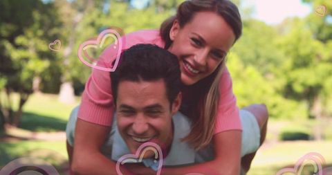 Joyful Couple Embracing Love in Sunlit Park with Heart Graphics