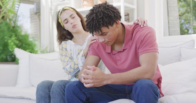 Sad biracial couple spending time at home together sitting on couch and cheering - Download Free Stock Photos Pikwizard.com