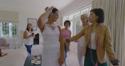 Bride in Wedding Dress with Supportive Friends and Family Amid Fitting