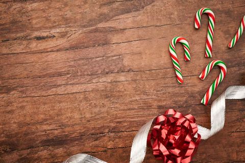 Colorful candy canes with red ribbon bows photo on wooden surface