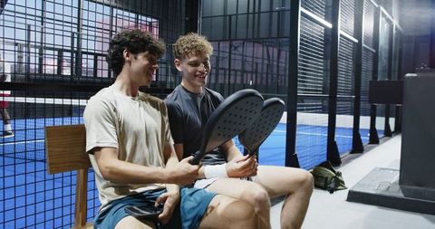Male Friends Examining Padel Rackets in Sports Facility