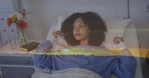 Reclining woman reflecting on recovery with sunset double exposure in hospital bed