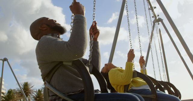Happy couple playing on playground swing in the park. Sunlight in the background 4k