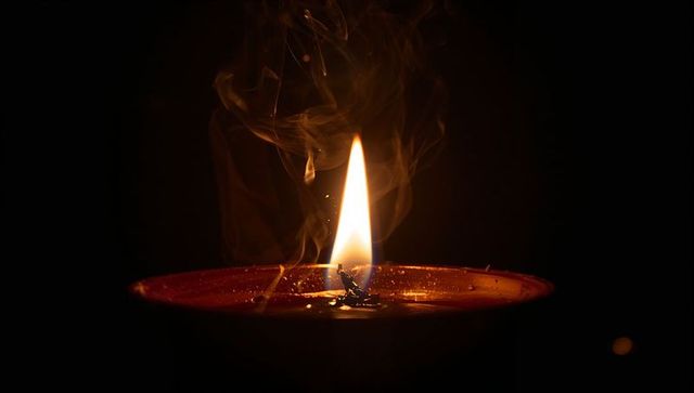 Tranquil Candle Flame with Smoky Ambiance in Darkness